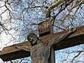jesus christ at some rusty cross under tree at some country road crossing